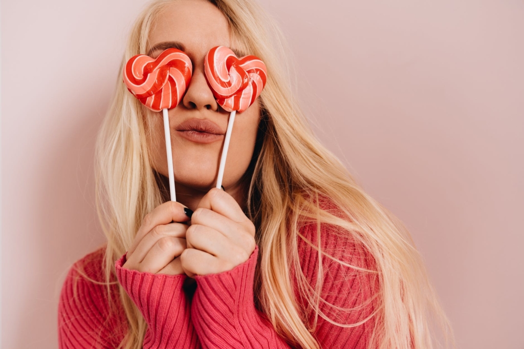 photo of woman holding heart shaped lollipops