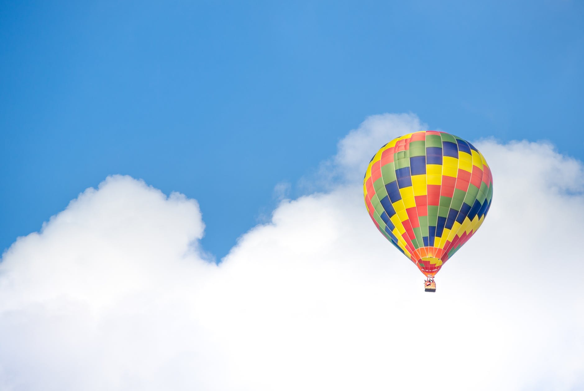 yellow blue and green hot air balloon flying near white clouds