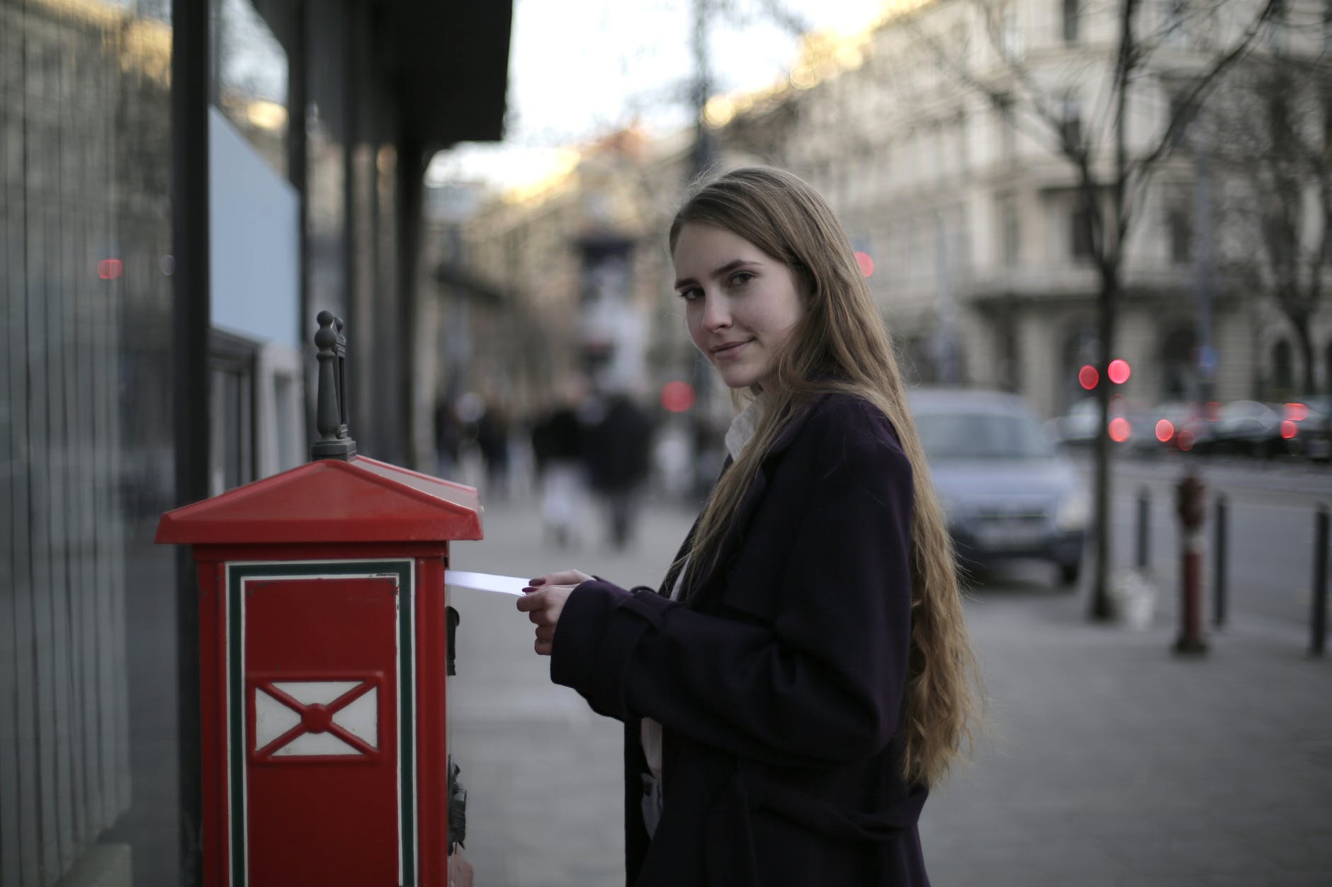 woman wearing violet coat while standing near mailbox